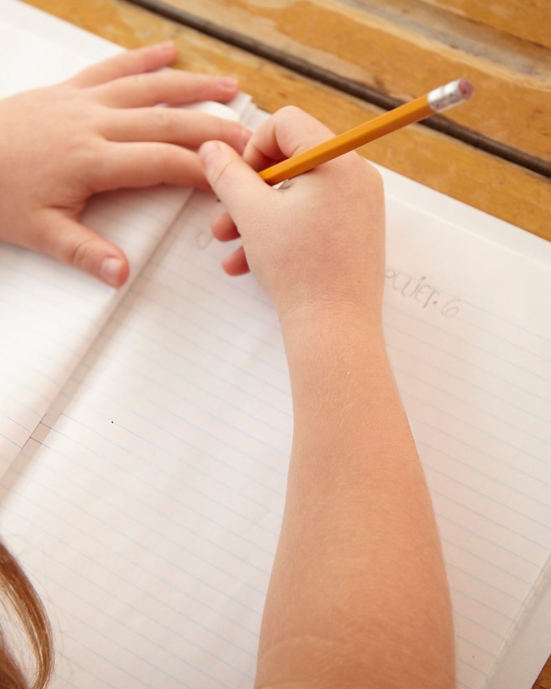Enfant qui écrit dans un cahier, accompagnement en orthopédagogie