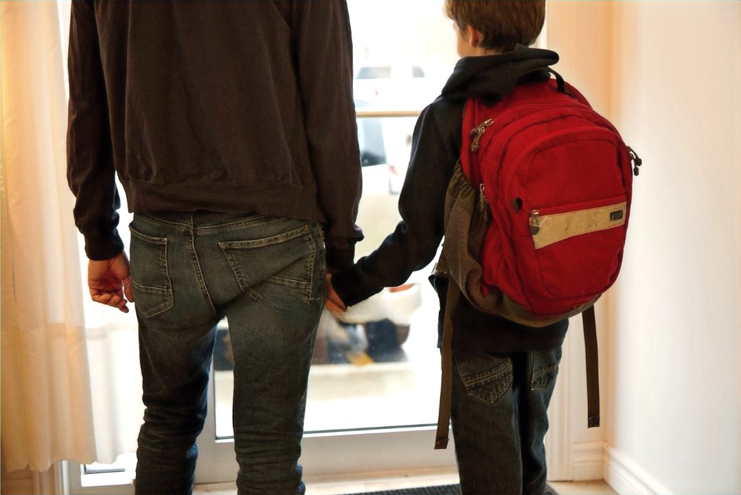 Parent qui tient la main de son enfant avant l'école